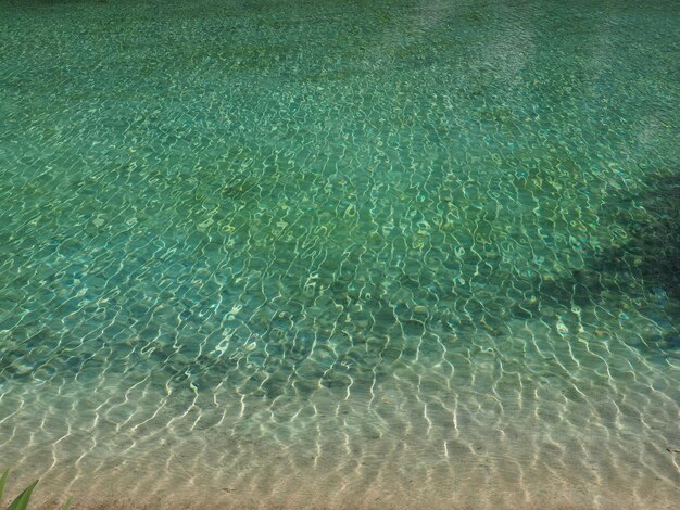 Água turquesa água do mar clara com ondas e brilho do sol o fundo é visível