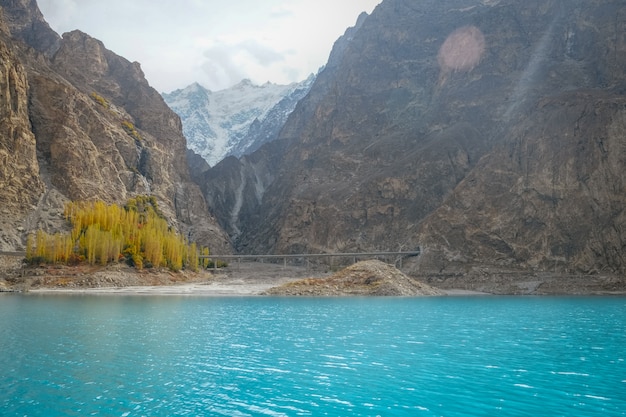 Foto agua turquesa del lago attabad en la temporada de otoño contra la cordillera nevada.