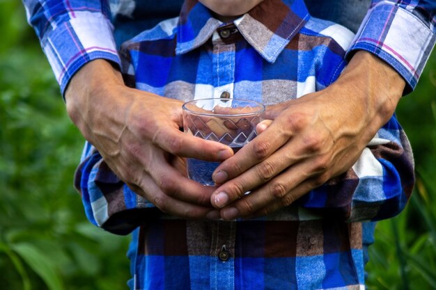 Agua en un vaso en manos de un niño y un padre. Naturaleza.