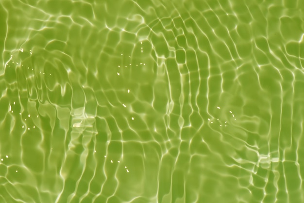 Agua verde en una piscina con el sol reflejado en la superficie del agua