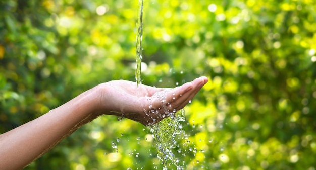 Agua vertiéndose en la mano en el fondo de la luz de la mañanaxD