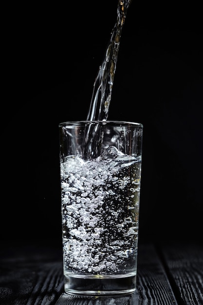 El agua se vierte en un vaso sobre un fondo negro