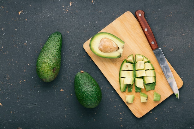 Foto aguacate y cuchillo sobre una tabla para cortar