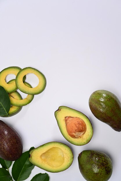 Aguacate fresco entero y en rodajas aislado sobre fondo blanco.