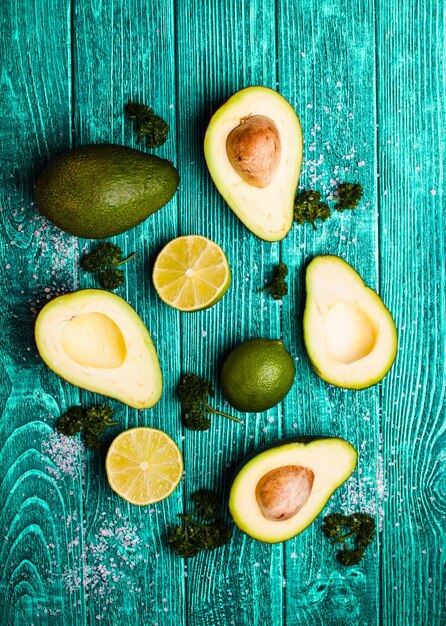 Aguacate fresco, lima, perejil y sal sobre fondo de madera azul antiguo