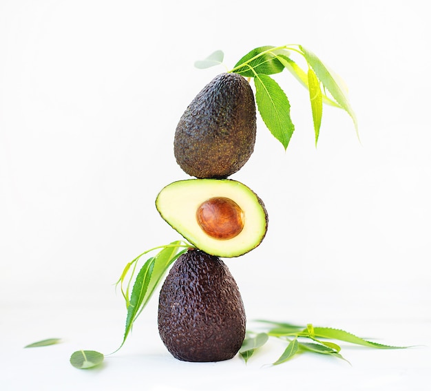 Aguacate Haas con hojas sobre un fondo blanco, enfoque selectivo, imagen creativa