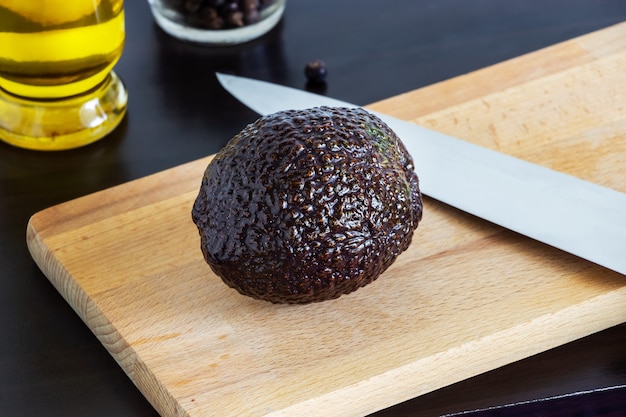 Aguacate maduro Haas sobre tabla para cortar. Fondo de madera oscura