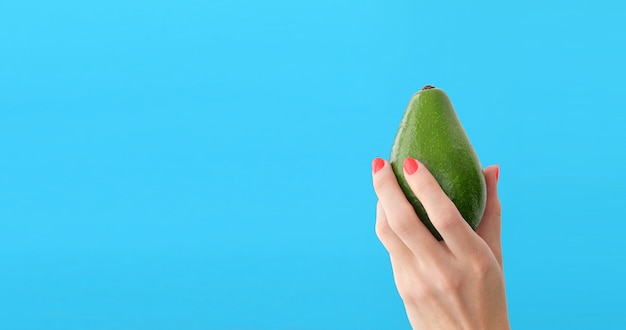 Aguacate en una mano de fondo azul mujer