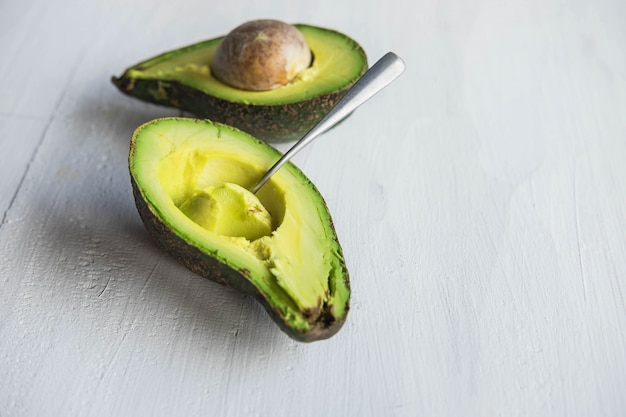 Aguacate medio cortado en una mesa de madera blanca