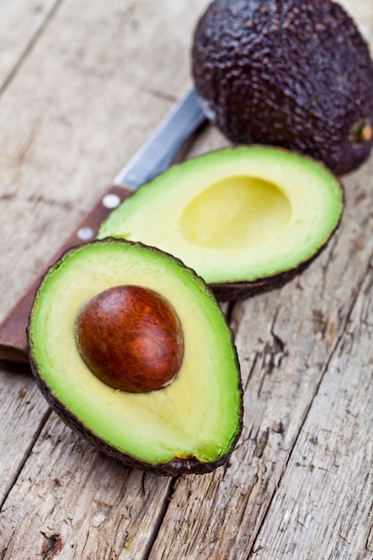 Aguacate orgánico fresco y cuchillo en mesa de madera vieja