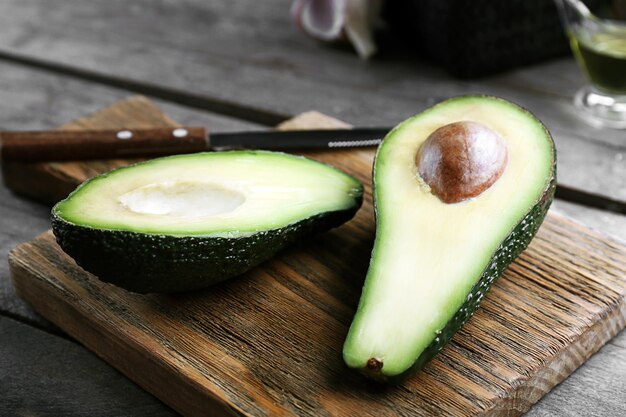 Aguacate en rodajas con cuchillo en tabla de cortar de madera