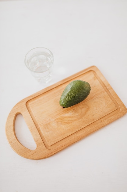 Aguacate y un vaso de agua sobre una tabla de madera. Concepto de salud y dieta