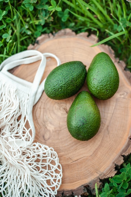 Foto aguacate verde fresco sobre una tabla de madera redonda bolsa de compras de malla ecológica en el marco