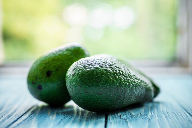 Aguacate verde en la pared de madera borrosa