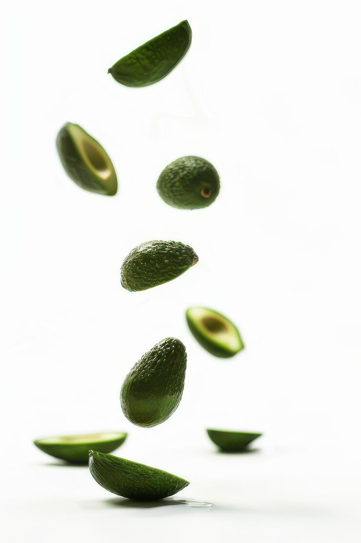 Aguacates y rebanadas de aguacate flotantes sobre un fondo blanco que muestran su color verde vibrante y textura fresca