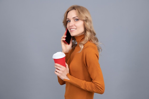 Aguarde um minuto, por favor. Mulher bonita fala no telefone segurando o copo. Tecnologia moderna. Comunicação móvel. Café móvel ou expresso a qualquer hora em qualquer lugar.