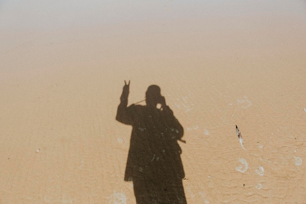 Águas calmas sobre a areia com a sombra de um homem