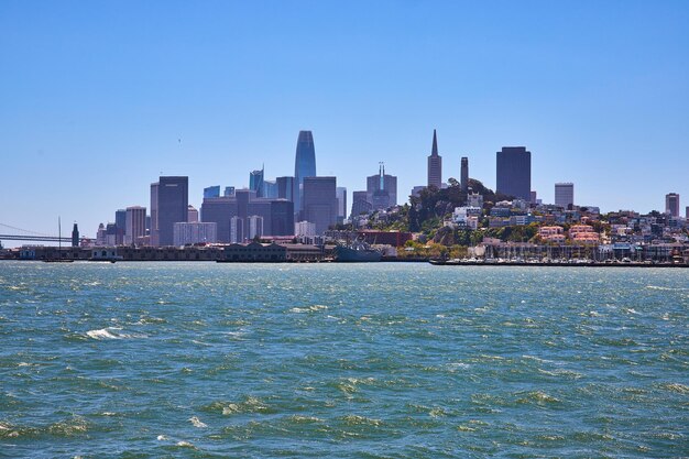 Las aguas turbulentas de la bahía de San Francisco con rascacielos distantes en el centro de la ciudad y muelles con barcos atracados