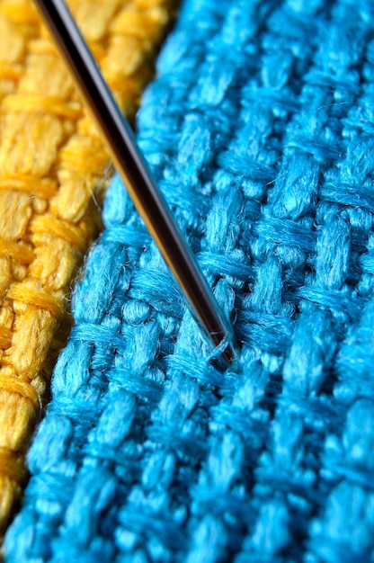 Aguja de coser en un primer plano de fondo de tela amarilla
