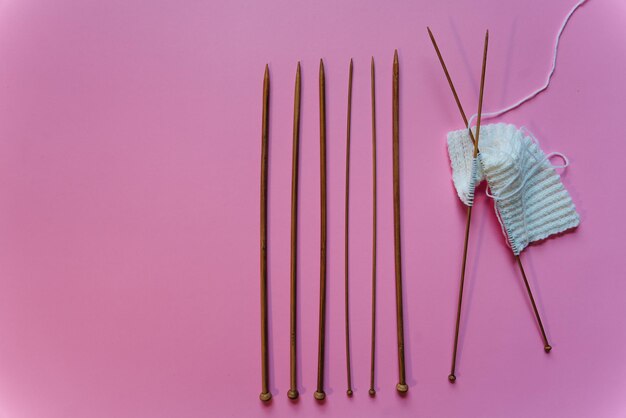 agujas de tejer en fondo rosa