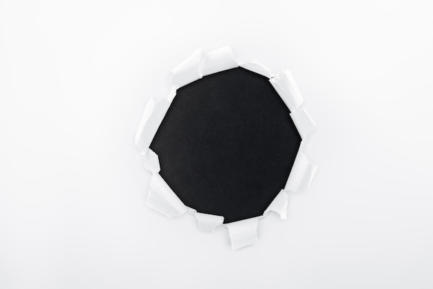 Foto agujero irregular en papel blanco texturizado sobre fondo negro