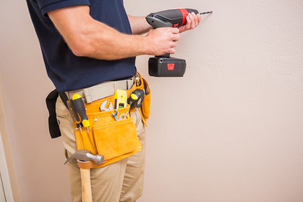 Agujero de perforación del trabajador de la construcción en la pared