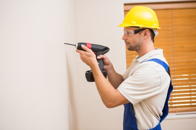 Agujero de perforación del trabajador de la construcción en la pared