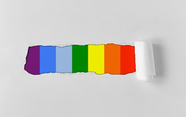 Un agujero reventado en papel con una bandera colorida lgbt