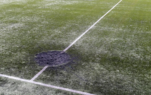 Un agujero en el suelo por la explosión de un proyectil de cañón lleno de tierra fresca en un estadio de fútbol