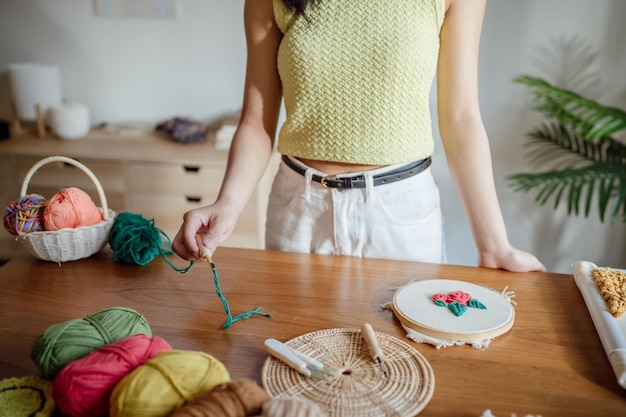 Agulha de punção Mulher asiática fazendo bordado à mão Hobby tricotar em estúdio oficina designer local de trabalho Projeto de artesanato à mão conceito de bordado DIY