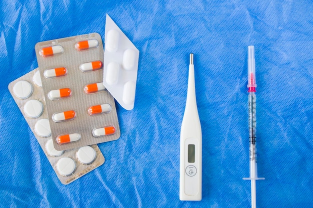 Agulha e ampola de medicamentos do termômetro corporal na mesa estéril