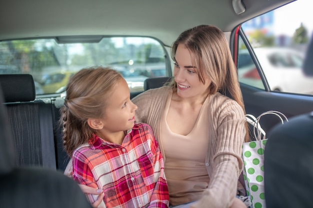 âHappy mamá e hija abrazándose en el asiento trasero del coche