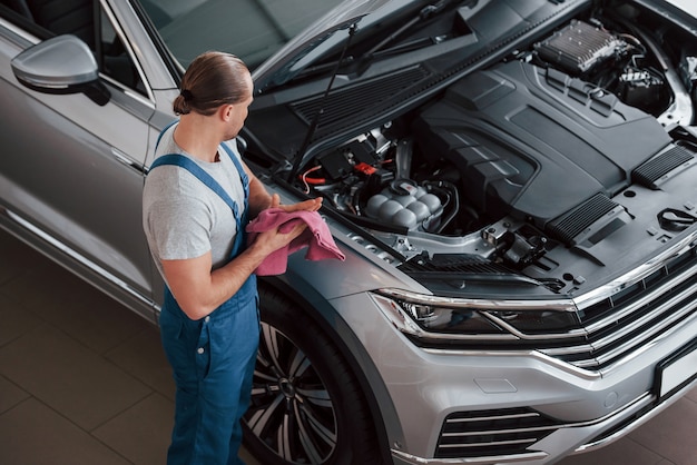 Ahora cabalgará. Hombre de uniforme azul trabaja con coche roto. Haciendo reparaciones