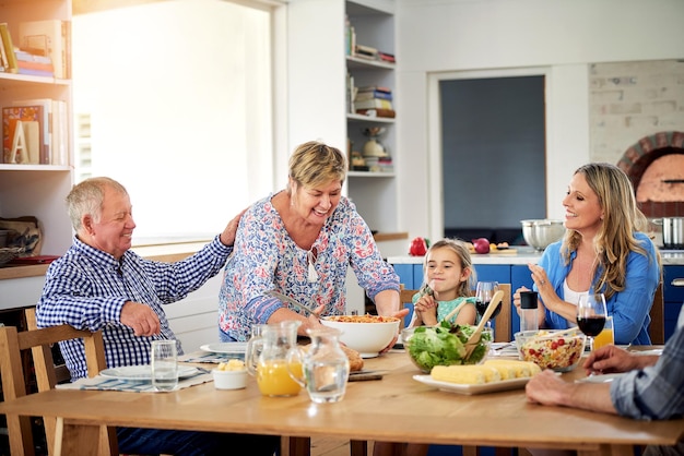 Ahora que la mesa está adornada, excave en Shot de una familia multigeneracional disfrutando de una comida juntos en casa