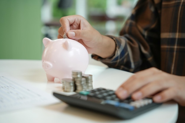 Ahorrando dinero mano poniendo dinero en la alcancía rosa haciendo inversiones