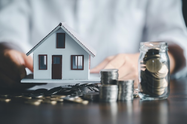 Ahorro de casa de inversión con concepto de negocio de dinero de financiación de préstamos Financiamiento de banca de inversión para negocios de bienes raíces residenciales Pila de monedas con casa modelo para préstamos de inversión Dinero en efectivo para impuestos