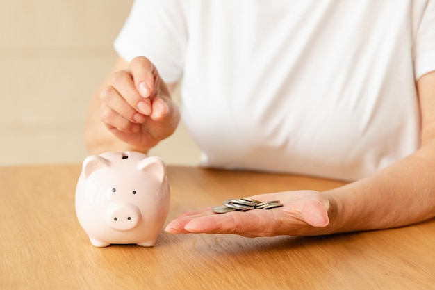 Ahorro de dinero inversión para el futuro anciano adulto mujer madura manos poniendo monedas de dinero en la alcancía