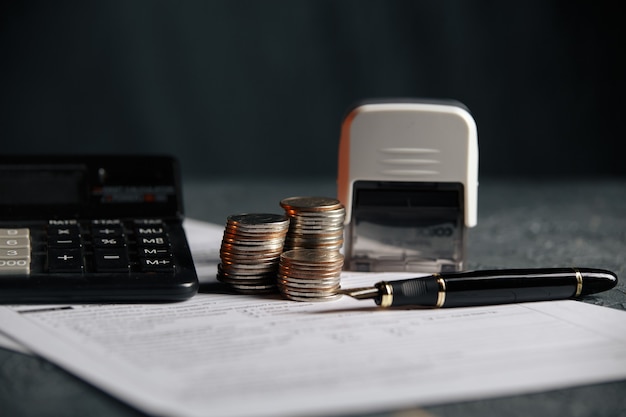 Ahorro de pila de monedas documento gráfico de dinero y bolígrafo en el escritorio