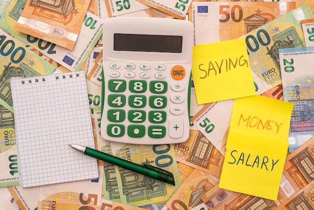 Ahorro de salario de texto en memorándum con calculadora y concepto financiero de dinero en euros