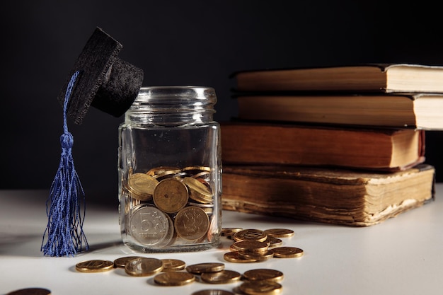 Ahorros para monedas de concepto de educación en tarro con dinero y gorro de graduación