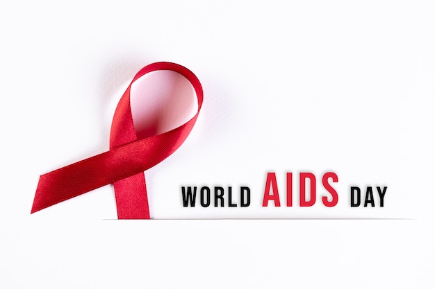 Foto aids awareness red ribbon em papel branco com texto. conceito do dia mundial da aids.