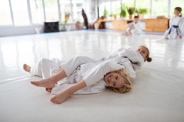 Aikido juntos. Niño y niña sonriendo mientras practica movimientos de aikido juntos