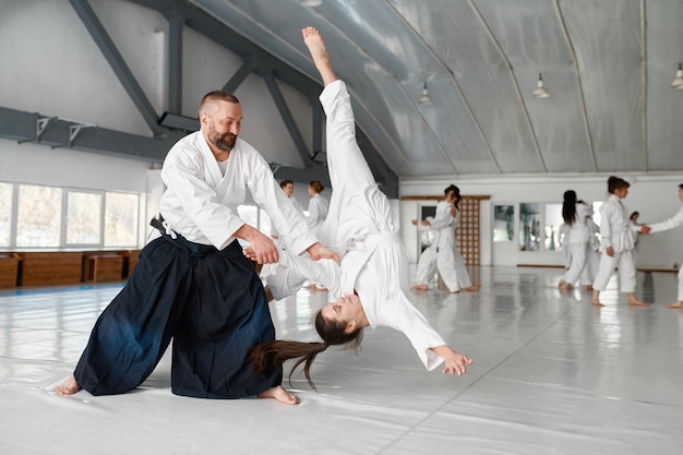 Aikido-Lehrer und -Schüler trainieren Werfen und Fallen