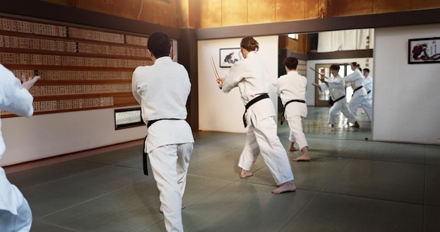 Aikido luta em grupo e bokken de artes marciais arma ou costas pretas estudantes em treinamento de ginásio ou dojo japoneses espada de madeira e clube para exercício treino ou aptidão em conflito com a batalha