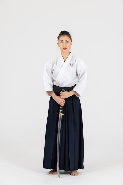 Aikido-Meisterfrau im traditionellen Samurai-Hakama-Kimono mit schwarzem Gürtel mit Schwert Katana auf weißem Hintergrund Gesunder Lebensstil und Sportkonzept