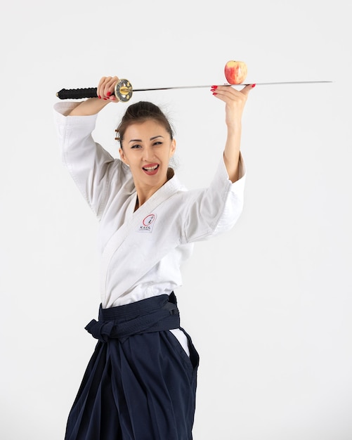 Aikido-Meisterfrau im traditionellen Samurai-Hakama-Kimono mit schwarzem Gürtel mit Schwert Katana auf weißem Hintergrund Gesunder Lebensstil und Sportkonzept