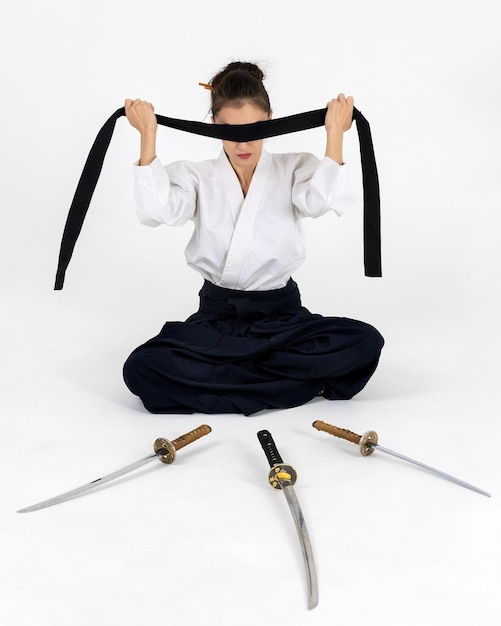 Foto aikido-meisterfrau im traditionellen samurai-hakama-kimono mit schwarzem gürtel mit schwert katana auf weißem hintergrund gesunder lebensstil und sportkonzept