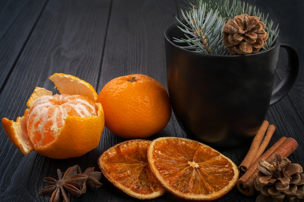 Ainda vida de Natal de inverno: tangerinas, laranjas secas, paus de canela e estrelas de anis em uma superfície preta texturizada