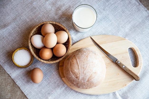 Ainda vida de pão, leite, ovos e sal em placas de madeira