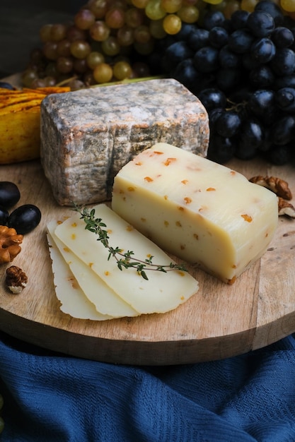 Ainda vida de variedade de placa de queijo. Frutas, faca e nozes com queijo diferente na placa de madeira